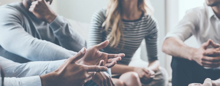 Close-up of people communicating while sitting in circle and gesturing