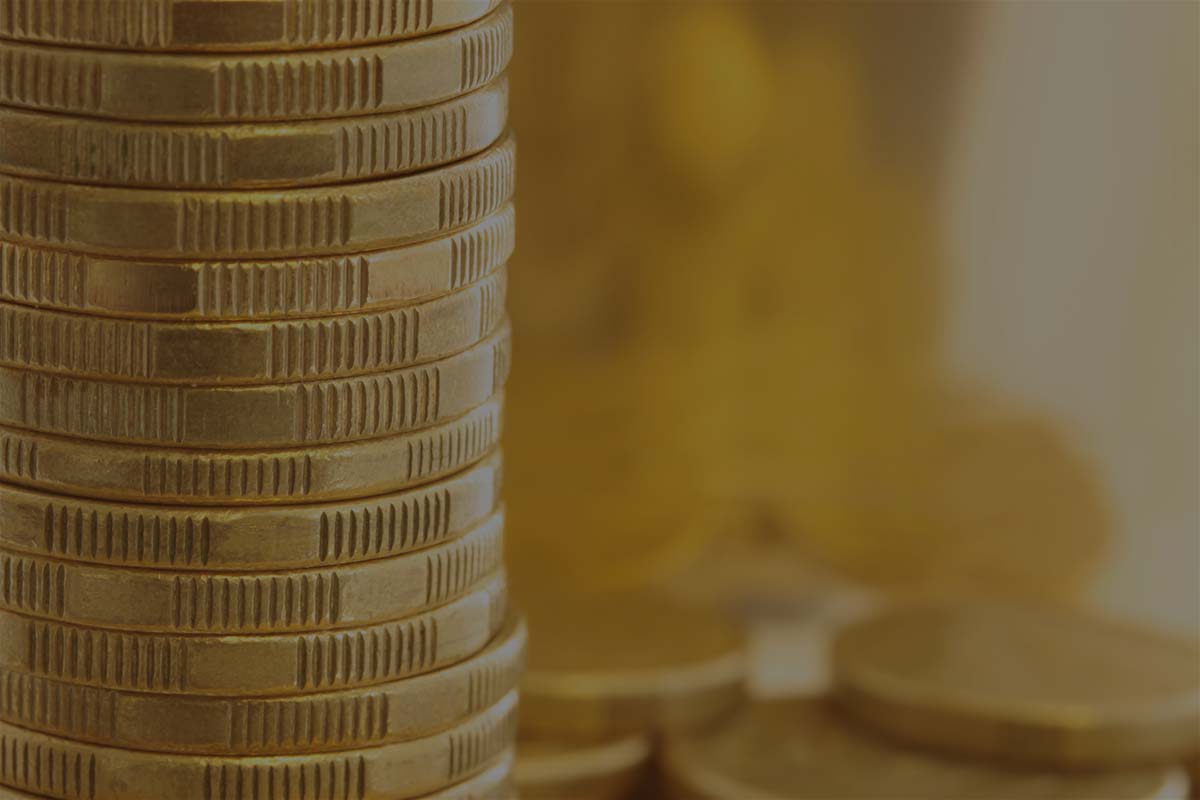 Gold coins in closeup, with golden light background.