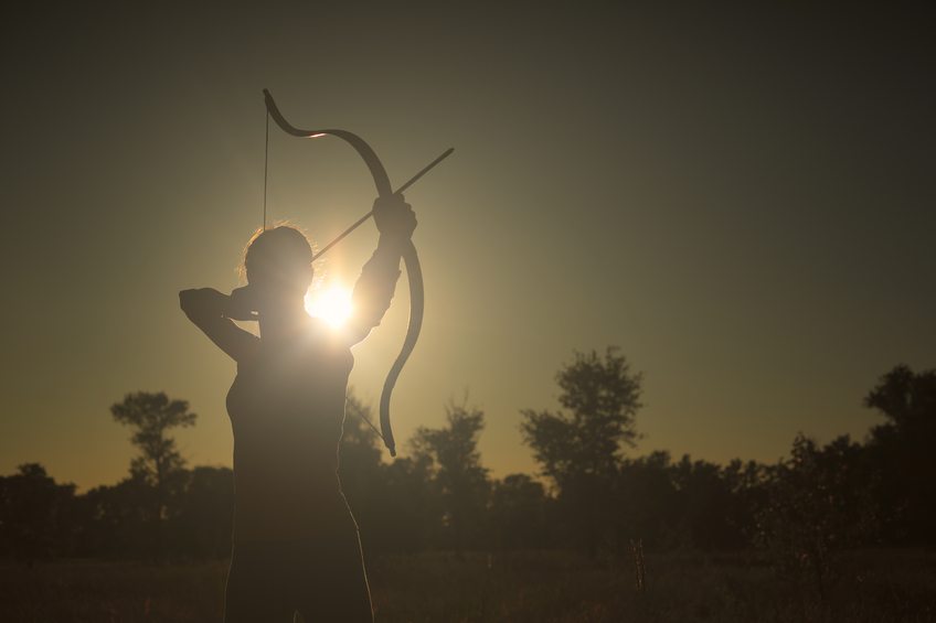 Female archer in the field at sunset