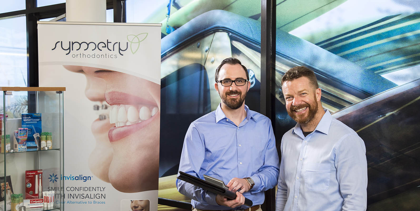 Accountant Jeremy Higgins with Jamie Galbraith standing in front of Symmetry Orthodontics banner 